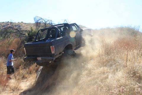 1992 Ford Bronco - A black 1992 Ford Bronco navigates a steep, dusty trail, demonstrating its off-road capabilities.