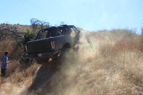 1992 Ford Bronco - A 1992 Ford Bronco navigates a challenging, dusty trail, kicking up a cloud of dirt.