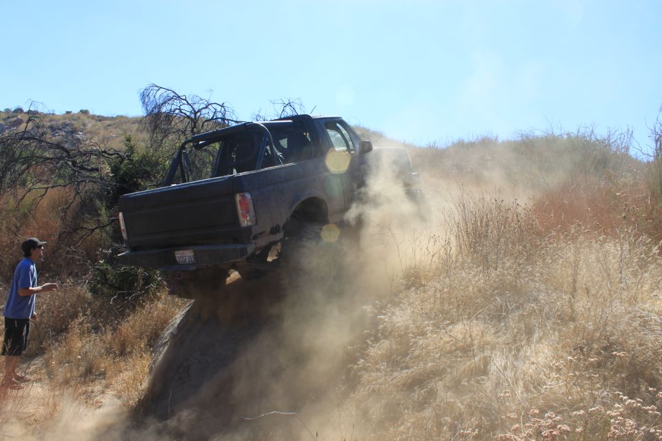 Black 1992 Ford Bronco climbing a steep, dusty hill off-road