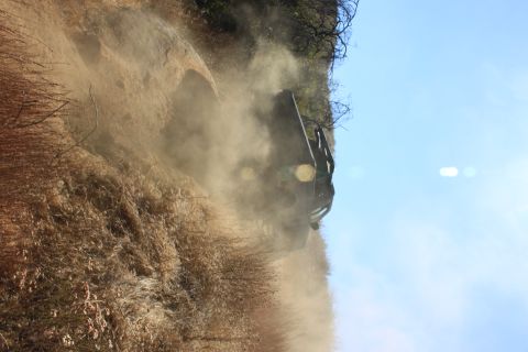 1992 Ford Bronco - A vehicle navigates a challenging, dusty incline under a clear blue sky.