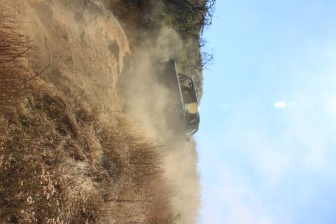 1992 Ford Bronco - An off-road vehicle navigates a steep, dusty trail under a bright blue sky.