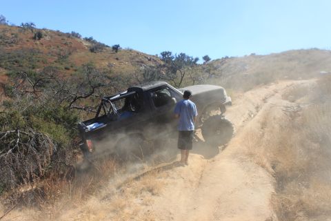 1992 Ford Bronco - A modified off-road vehicle navigates a dusty trail on a sunny day.