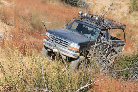 1992 Ford Bronco - 1992 Ford Bronco tackling rough terrain on a dry, grassy slope.