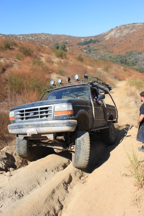 1992 Ford Bronco - This 1992 Ford Bronco navigates a challenging sandy trail with a person standing nearby.