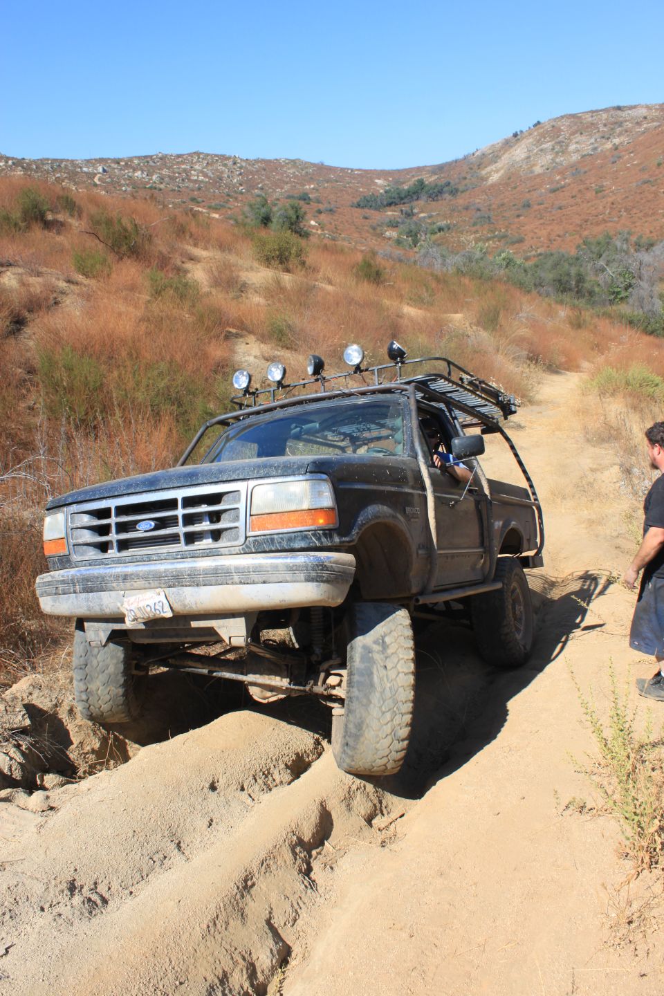 1992 Ford Bronco off-roading on a sandy trail, front 3/4 view