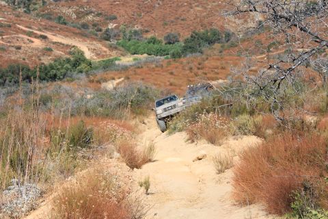 1992 Ford Bronco - This 1992 Ford Bronco navigates a challenging off-road trail surrounded by dry brush and hills.