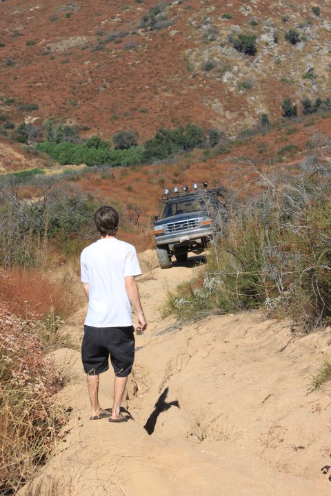 1992 Ford Bronco - A 1992 Ford Bronco navigates an off-road trail in a hilly, dry landscape.