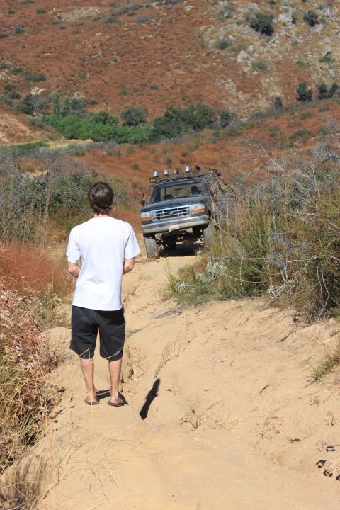 1992 Ford Bronco - A 1992 Ford Bronco navigates a steep, dusty trail in a hilly, arid landscape.