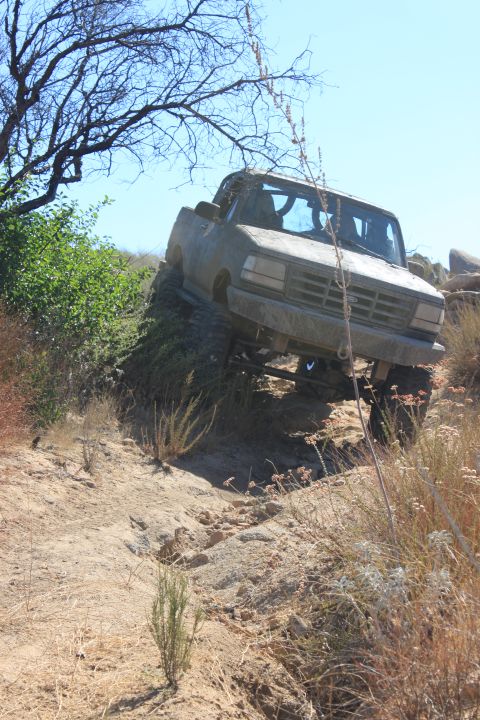1992 Ford Bronco - A 1992 Ford Bronco navigates a steep, rocky incline on a sunny day.