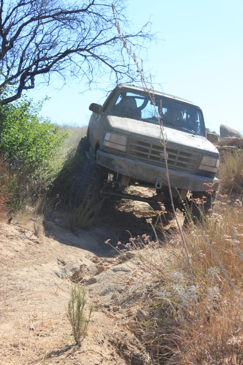 1992 Ford Bronco - A 1992 Ford Bronco navigates a challenging off-road trail with steep inclines and rocky terrain.