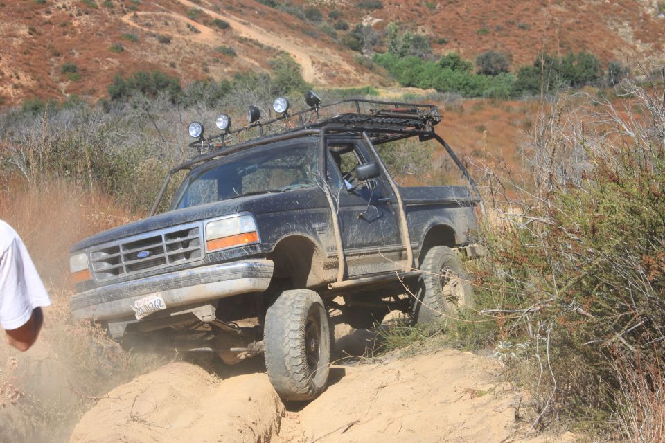1992 Ford Bronco off-roading on a dusty trail with a roof rack