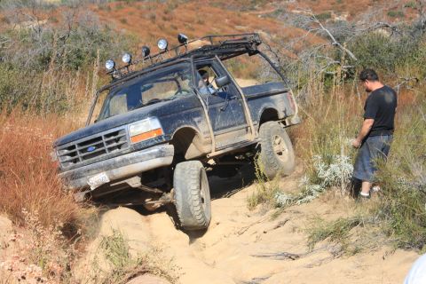 1992 Ford Bronco - A 1992 Ford Bronco tackles a challenging off-road trail with a driver and observer present.