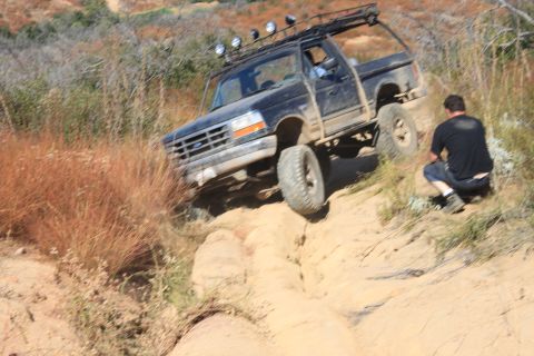 1992 Ford Bronco - A black 1992 Ford Bronco navigates a steep, sandy incline with a man observing the action.