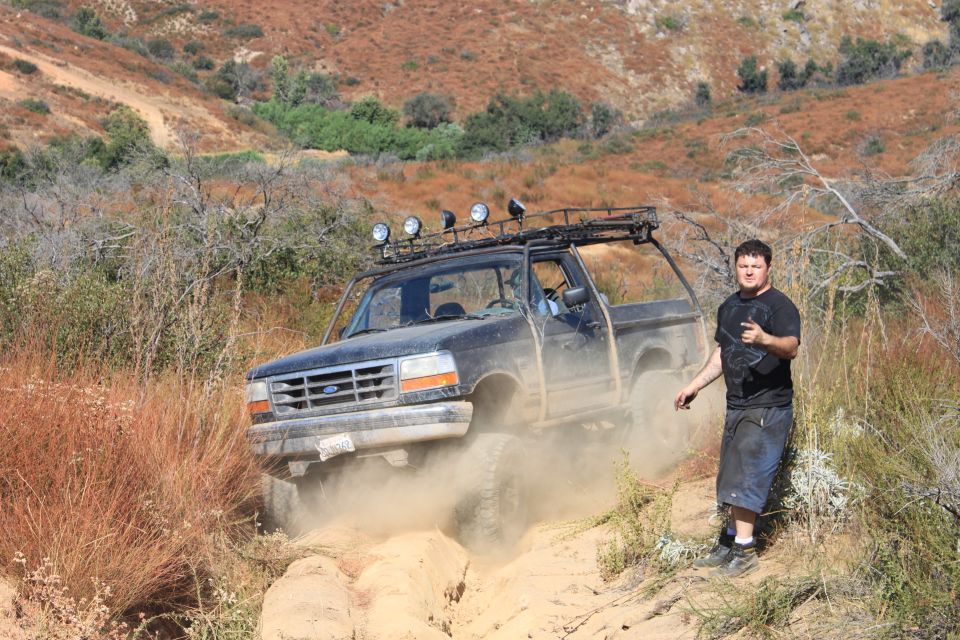 Black 1992 Ford Bronco kicking up dust on a dirt trail