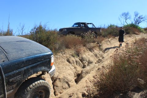 1992 Ford Bronco - Two Broncos navigate a challenging off-road trail under a clear blue sky.