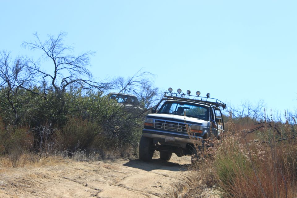 White 1992 Ford Bronco with roof lights driving off-road