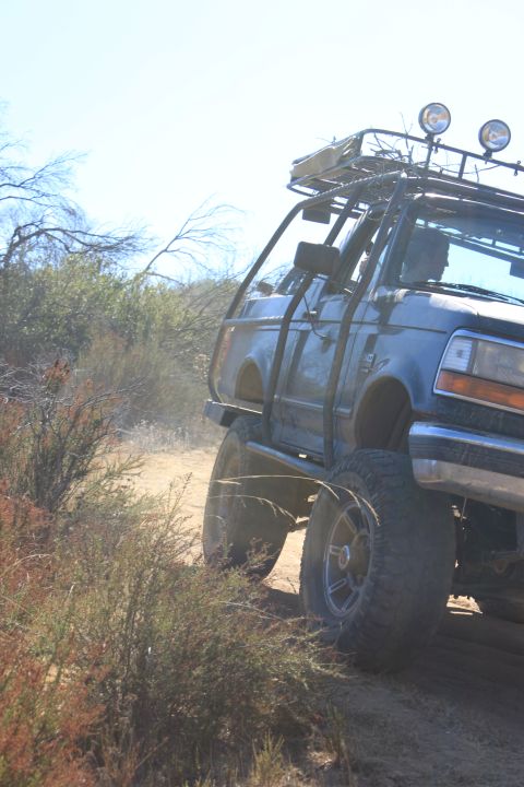 1992 Ford Bronco - This modified 1992 Ford Bronco navigates a dusty trail, equipped with an external roll cage and a roof rack.