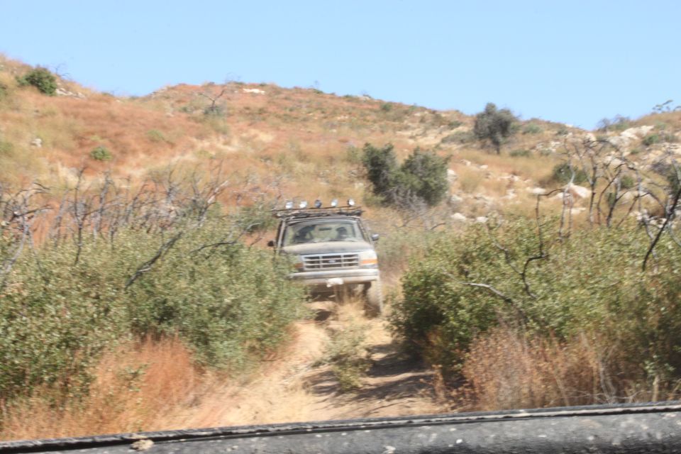 1992 Ford Bronco on a dirt trail with brush and hills