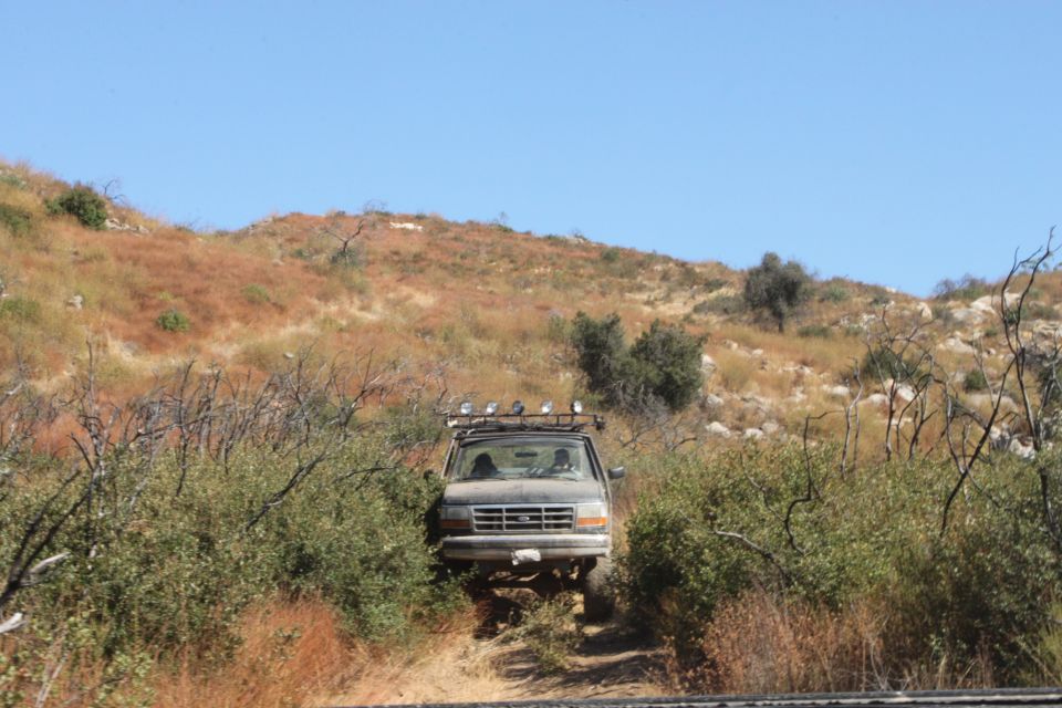 Ford F-Series truck driving on a dirt trail through brush