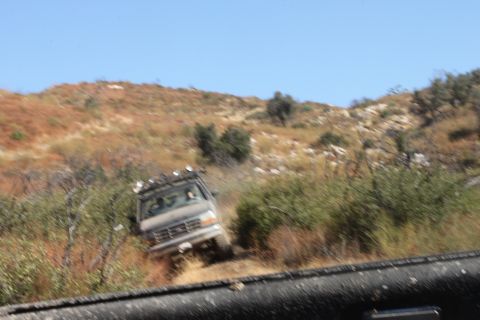 1992 Ford Bronco - A vehicle navigates a rough, dry, outdoor terrain under a clear blue sky.