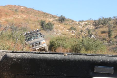 1992 Ford Bronco - A gray Ford Econoline van navigates a dusty off-road trail with a roof rack and auxiliary lights.