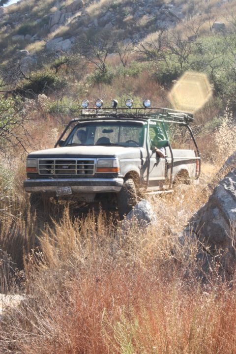 1992 Ford Bronco - This modified 1992 Ford Bronco navigates a rocky, dry terrain, equipped for off-road adventures with a prominent roof rack and auxiliary li…