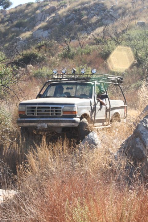 1992 Ford Bronco - A modified Ford F-Series truck navigates a , dry, and rocky terrain.