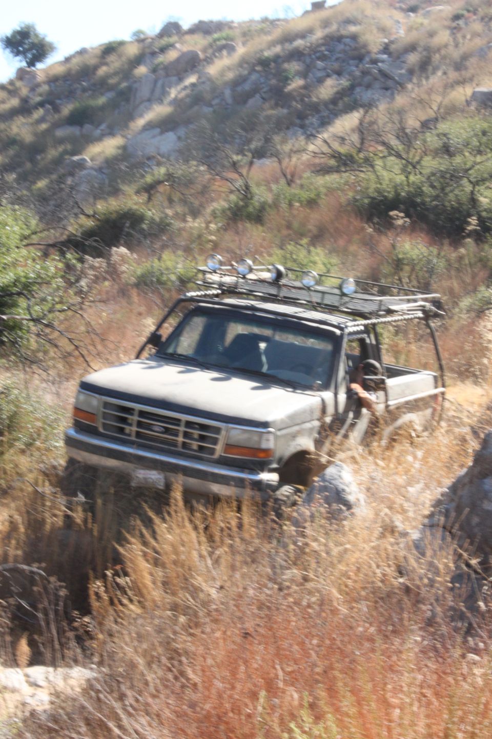 Gray 1992 Ford Bronco on a rocky hillside with a roof rack