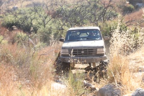 1992 Ford Bronco - A 1992 Ford Bronco is shown off-roading through a dry, brushy landscape.