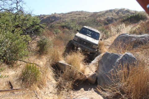 1992 Ford Bronco - This 1992 Ford Bronco is shown navigating a challenging off-road course with large rocks and dry vegetation.