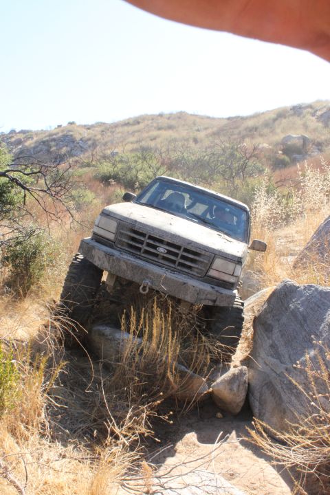 1992 Ford Bronco - This 1992 Ford Bronco is shown navigating a challenging off-road course with large rocks and dry brush.