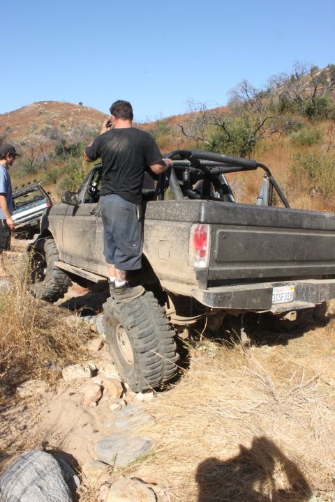 1992 Ford Bronco - A modified 1992 Ford Bronco with a roll cage and large off-road tires navigates a rocky trail, with another vehicle visible in the backgrou…