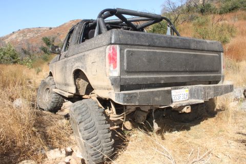 1992 Ford Bronco - This Ford Bronco is navigating a rough, dry, outdoor terrain with large tires.