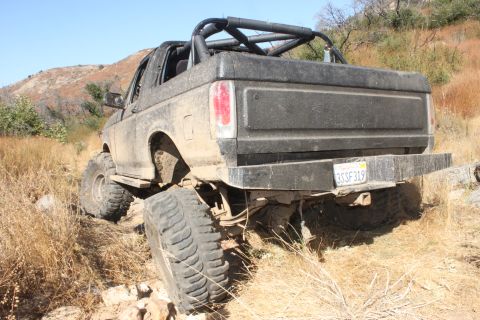 1992 Ford Bronco - A heavily modified black Ford Bronco navigates a challenging off-road trail.