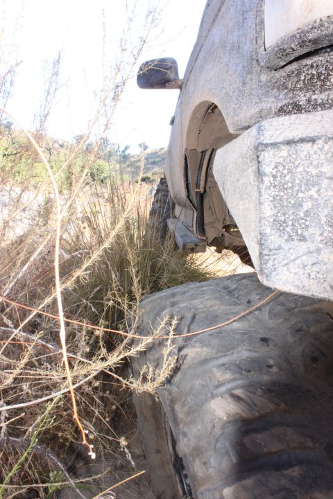 1992 Ford Bronco - A vehicle navigates rough terrain, with its tire and fender covered in mud.