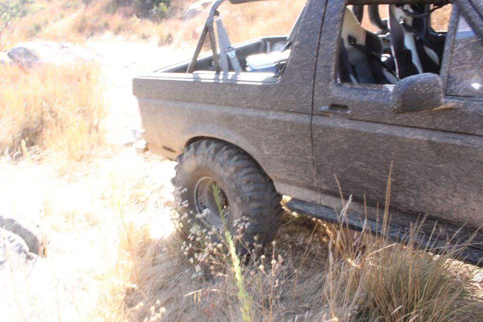Mud-covered 1992 Ford Bronco side view, off-road tires, roll cage, racing seats