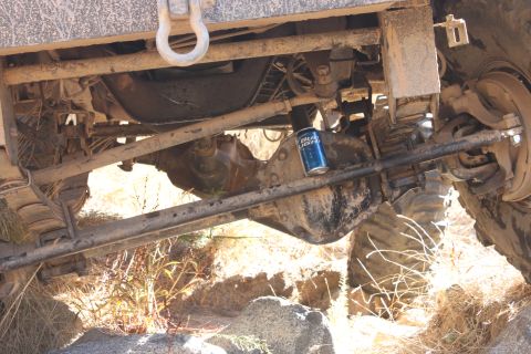 1992 Ford Bronco - A can of beer sits on the axle of a off-road vehicle, highlighting its undercarriage components.