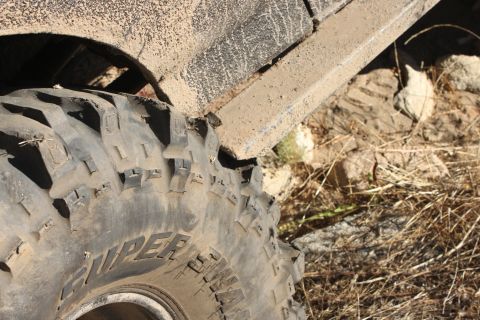 1992 Ford Bronco - A close-up view of a heavily soiled tire and fender suggests off-road use on a dry, rocky landscape.