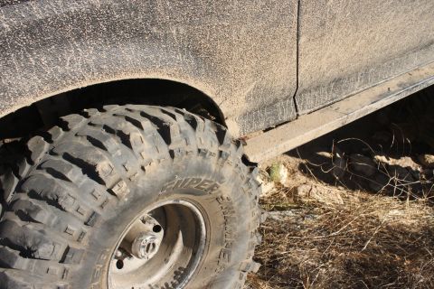 1992 Ford Bronco - Close-up of a muddy off-road tire and fender flare on a vehicle.