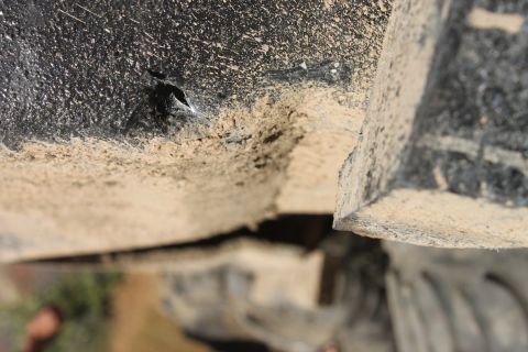 1992 Ford Bronco - Undercarriage detail of a vehicle, showing dirt and a small hole in the fender.