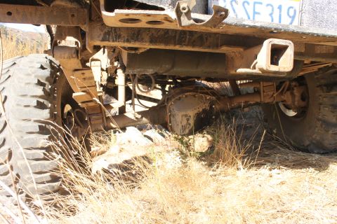 1992 Ford Bronco - The underside of a vehicle, showing the rear axle, leaf springs, and a partial license plate, is captured in this off-road scene.