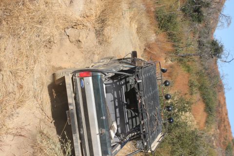 1992 Ford Bronco - A green 1992 Ford Bronco navigates a dusty, off-road trail with a prominent roof rack.