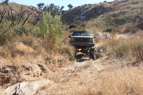 1992 Ford Bronco - A 1992 Ford Bronco navigates a rough, dry, off-road trail with large tires and a lifted suspension.