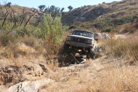 1992 Ford Bronco - This 1992 Ford Bronco is tackling a challenging off-road trail with significant elevation changes.