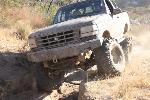 1992 Ford Bronco - This 1992 Ford Bronco is tackling a challenging off-road course with significant mud and rocks.