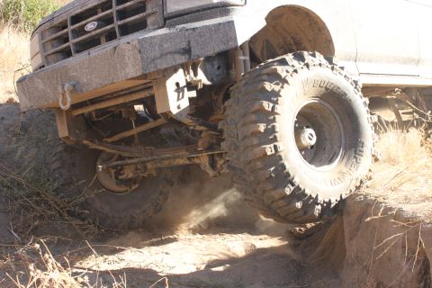 1992 Ford Bronco - A heavily modified Ford truck navigates a challenging off-road obstacle.