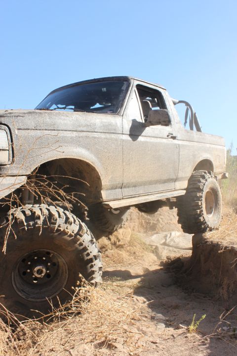 1992 Ford Bronco - This 1992 Ford Bronco navigates a challenging off-road trail, its large tires gripping the dirt as it climbs.