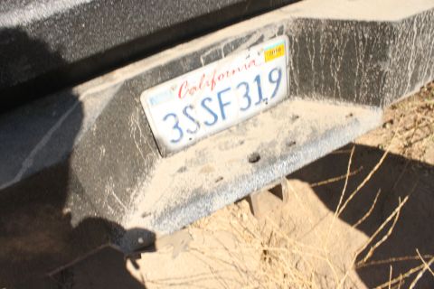 1992 Ford Bronco - A close-up of a vehicle's rear bumper shows a California license plate covered in dust.