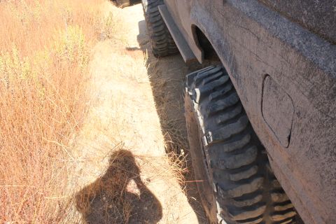 1992 Ford Bronco - Close-up of an off-road vehicle's tire and fender, seen on a dry, brushy terrain.