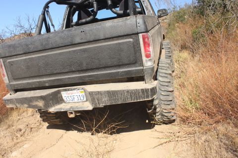 1992 Ford Bronco - This 1992 Ford Bronco is shown from the rear, navigating a dusty, off-road trail.